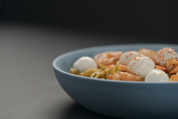 Penne pasta with shrimps and mozzarella and pesto in blue bowl with copy space