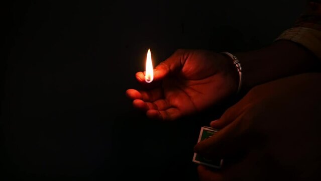 Close-up video of a man lighting up a match in the dark