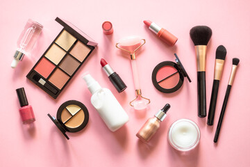 Makeup cosmetic products on pink background. Cream, lipstick, shadow and brushes. Flat lay image with copy space.