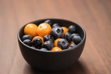Blueberries with physalis in a bowl on wood table