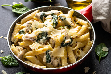 Pasta penne with chicken and spinach in creamy sauce in the skillet.