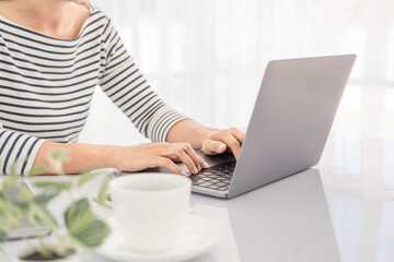 Asian business woman in casual clothes, Hand typing text on laptop in a bright modern office with copy space.