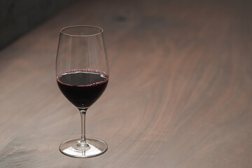 Red wine in wineglass on black walnut table with copy space