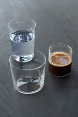 Ingredients for espresso tonic with clear ice cube in tumbler glass on oak wood table with copy space