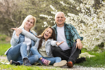 Fototapeta premium family having picnic in park, garden with flowering trees, spring