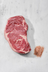 Raw beef fillet steaks with pink salt on white marble background, top view. 