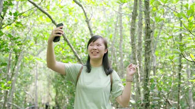 Woman visiting the mangrove forest taking photos and video calling