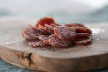 Sliced cured sausage on olive serving board