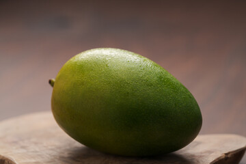 Ripe green mango washed and ready to eat on wood board