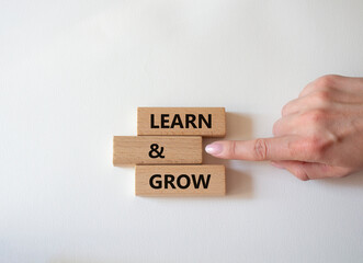 Learn and grow symbol. Concept words 'Learn and grow' on wooden blocks. Beautiful white background. Businessman hand. Business and Learn and grow concept. Copy space.