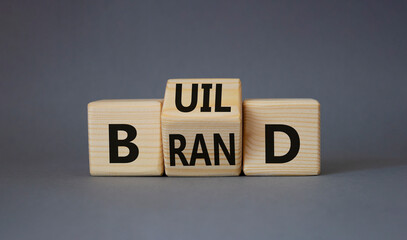 Build your brand symbol. Turned wooden cubes with words Build and Brand. Beautiful grey background....