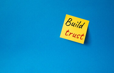 Build trust symbol. Orange steaky note with words Build trust. Beautiful blue background. Business and Build trust concept. Copy space.