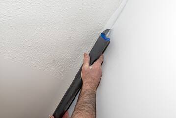A man applies ready-made polymer plaster from a bucket using special plaster cutters.