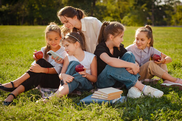 Fototapeta premium Group of school kids relaxing after classes. children spend time with gadgets outdoors