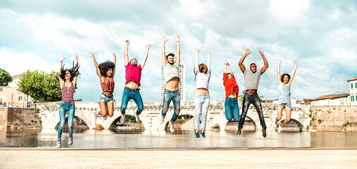 Diverse multi racial friends jumping at Rimini city - Happy urban  guys and girls having fun around old town location - University students on travel life style vacation concept - Bright warm filter - obrazy, fototapety, plakaty