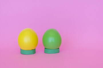 Easter eggs in a vertical position of yellow and green on a pink background.