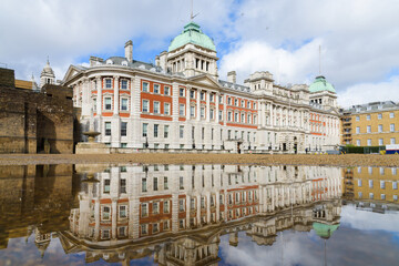 Old Admiralty Building reflects in a puddle on Horse Guards Parade in London