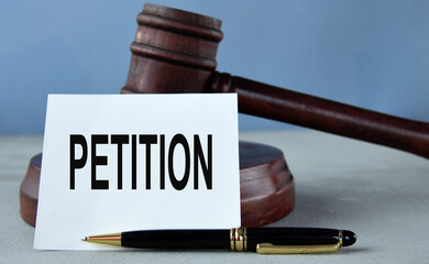 PETITION - word on a white sheet against the background of a judge's hammer and a wooden stand