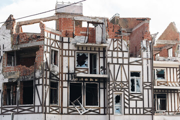 Destroyed building after russian invasion, Gostomel, Ukraine. Ruined facade of house with fachwerk design. War in Ukraine. Broken windows and brick walls after missile attack. Abandoned damaged home.