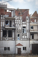 Destroyed building after russian invasion, Gostomel, Ukraine. Ruined facade of house with fachwerk design. War in Ukraine. Broken windows and brick walls after missile attack. Abandoned damaged home.