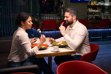 Smiling female and male having dinner together