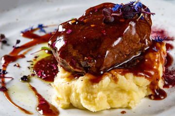Stewed veal cheeks with mashed potatoes on plate