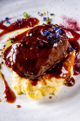 Stewed veal cheeks with mashed potatoes on plate