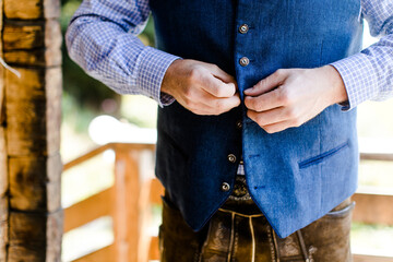 Br&auml;utigam in Lederhose kn&ouml;pft sich die Trachtenweste zu