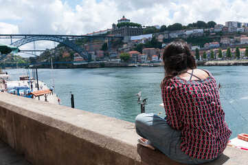 Una mujer lee al lado del río Duero en la ciudad de Porto en Portugal.