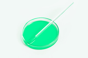 Petri dish for laboratory with green liquid. Pipette, glass tube. On a white, light background.