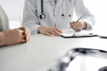 Doctor and patient discussing current health examination while sitting at the desk in clinic...