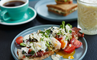 Gourmet sandwich with poached egg, cherry tomatoes and micro greens served for lunch in a restaurant