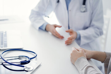 Stethoscope lying on the tablet computer in front of a doctor and patient at the background . Medicine, healthcare, reasuring hands concept.