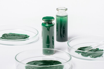 A solution or oil from spirulina in a jar. Spirulina powder in a jar. On a white background. Petri dishes with maxa or spirulina cream.