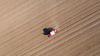 Aerial view on tractor as spread fertilizer over agricultural field