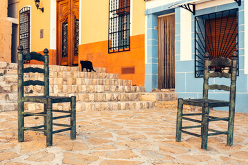 Fototapeta na wymiar Cozy little square with two chairs and beautiful narrow streets in old town of Finestrat, Alicante province, Costa Blanca, Spain