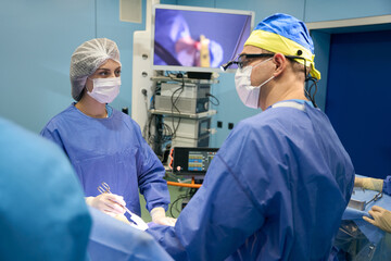 Surgeon with assistants operates on patient in sterile operating room