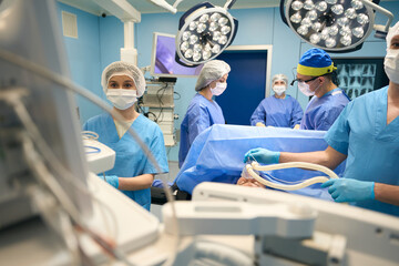 Anesthesiologist, surgeon, assistants stand at the operating table above patient