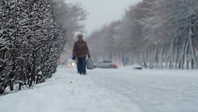Urban male pedestrian in a snowfall blizzard on a city street in cold snowy winter weather
