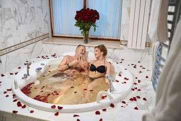 Loving couple basks in a bath with rose petals