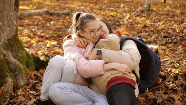 A happy mother hugs her two daughters in the autumn forest.