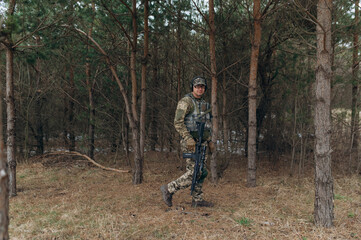 a soldier walks through the forest with a machine gun. military in full-length camouflage
