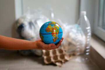 the globe in the hands of a child against the background of garbage, save the planet, call