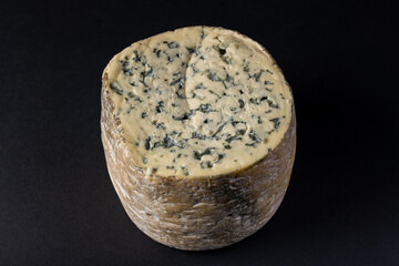 Piece of blue Fourme d' Ambert French cheese isolated on a black background