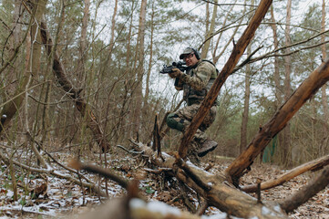 military man in camouflage uniform on tree branches, in an ambush with a weapon, a machine gun.