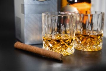 Two glasses of whiskey and a cigar on a black background.High quality photo