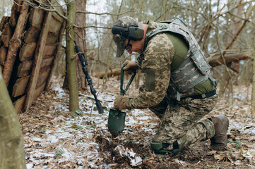 a soldier with a shovel in his hand digs the ground. an infantryman digs a hole
