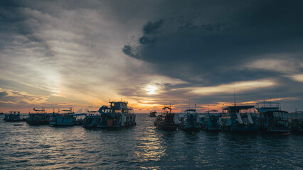 Fototapeta premium Fishing boats lined up against the blue and orange sunset on Koh Tao Thailand Island