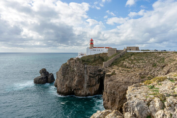 Fototapeta na wymiar Lighthouse of Cabo de São Vicente. View of idyllic nature landscape with rocky cliff shore and waves crashing on. Sagres, Portugal on February 27, 2023
