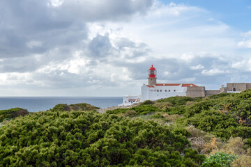 Fototapeta na wymiar SAGRES, PORTUGAL - FEBRUARY 27, 2023: Lighthouse of Cabo de São Vicente. View of idyllic nature landscape with rocky cliff shore and waves crashing on. Sagres, Portugal on February 27, 2023 